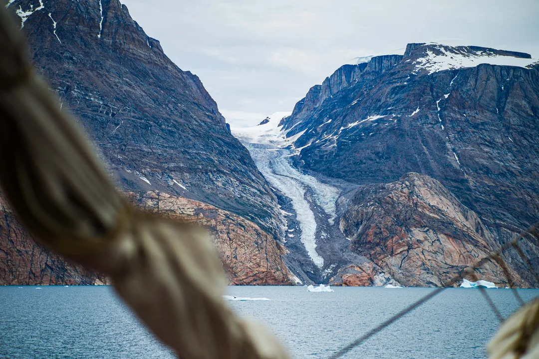 Glacier descending between dark mountain slopes toward Scoresby Sund.