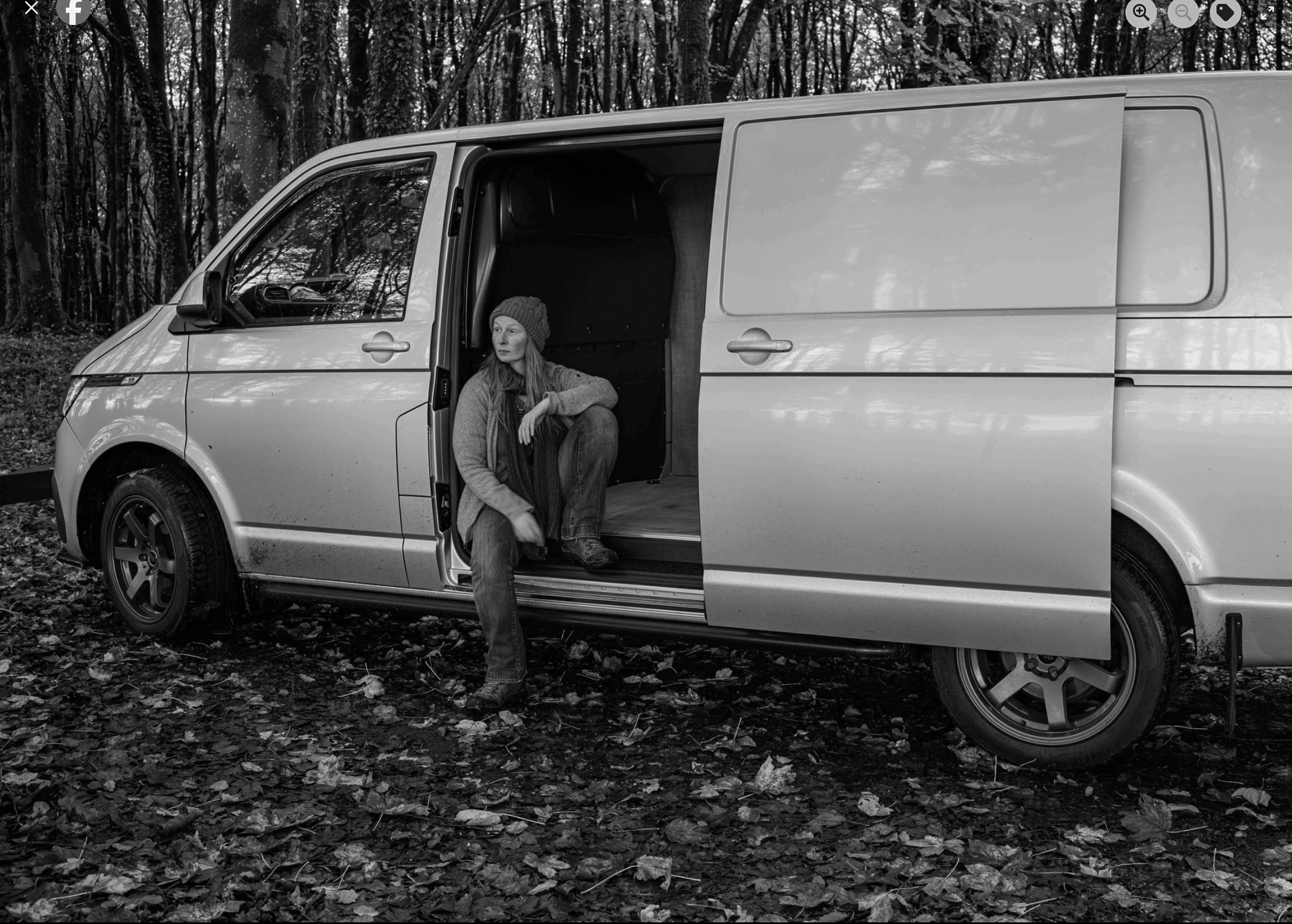 Aishling Muller seated in the doorway of the EOS mobile field studio in woodland.